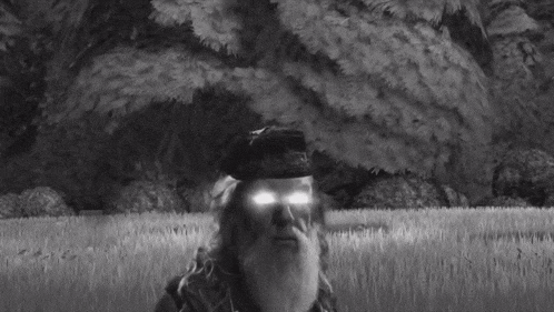 a black and white photo of a man with glowing eyes and a hat .