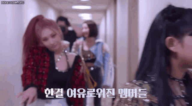 a group of women are walking down a hallway with korean writing on the walls .