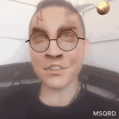 a man wearing glasses has a golden snitch on his head