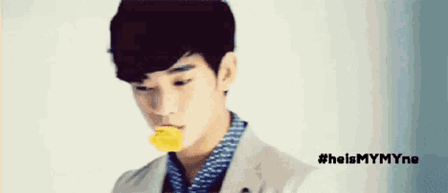 a young man holding a yellow flower in his mouth with the hashtag #helpmymyne written below him