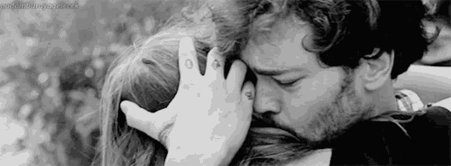 a black and white photo of a man kissing a woman 's forehead .