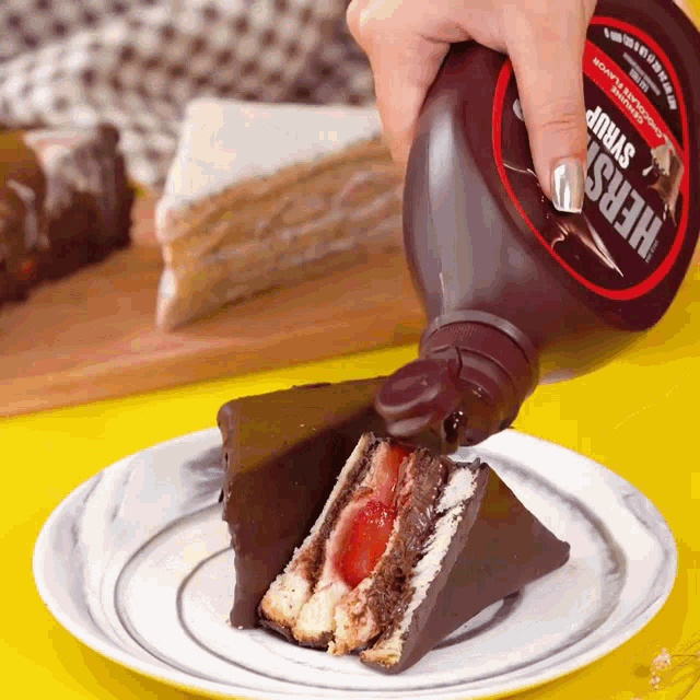 a bottle of hershey syrup is being poured on a piece of chocolate cake