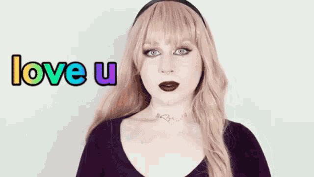 a woman with pink hair and a choker is standing in front of a white wall and says `` love u '' .