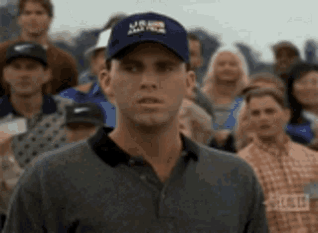 a man wearing a blue hat with the word usa on it stands in front of a crowd of people