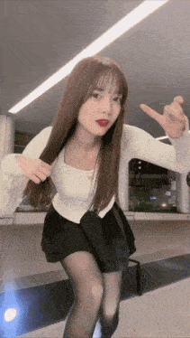 a woman in a white top and black skirt is making a peace sign