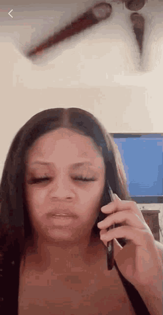 a woman is talking on a cell phone with her eyes closed .