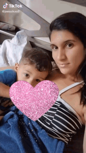 a woman is holding a baby with a pink heart in front of her