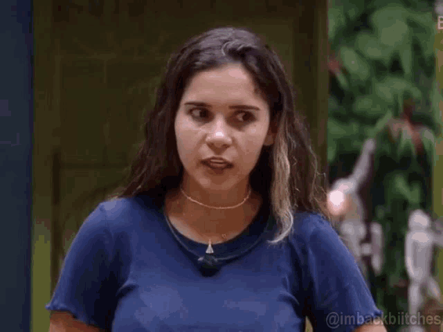 a woman wearing a blue shirt and a choker is standing in front of a door .