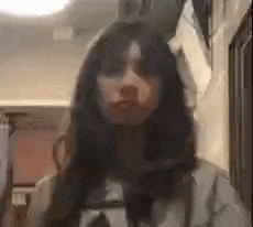 a woman with long hair is standing in a hallway with a blurred image of her face .