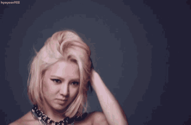 a woman with blonde hair is wearing a black top and a necklace