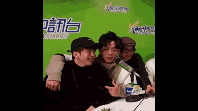 a group of young men are sitting at a table in front of a microphone in a studio .