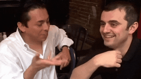 two men are sitting next to each other and one is pointing at the other