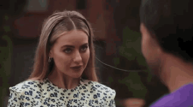 a woman wearing a leopard print top smiles while looking at a man in a purple shirt