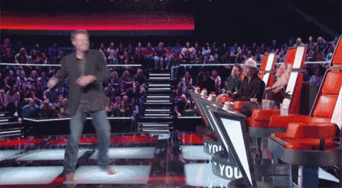 a man is dancing on a stage with a sign that says " you "