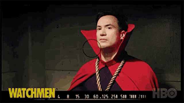 a man in a red cape with a rope around his neck is standing in front of a sign that says watchmen .