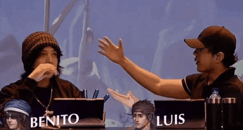 benito and luis are sitting at a table with their hands outstretched