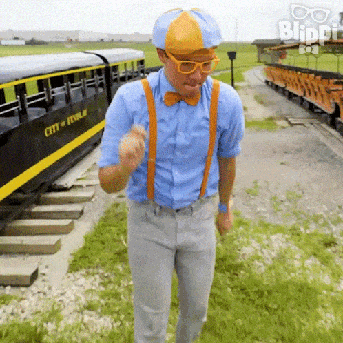 a man in a blue shirt and orange suspenders is standing in front of a train that says city of pennsylvania
