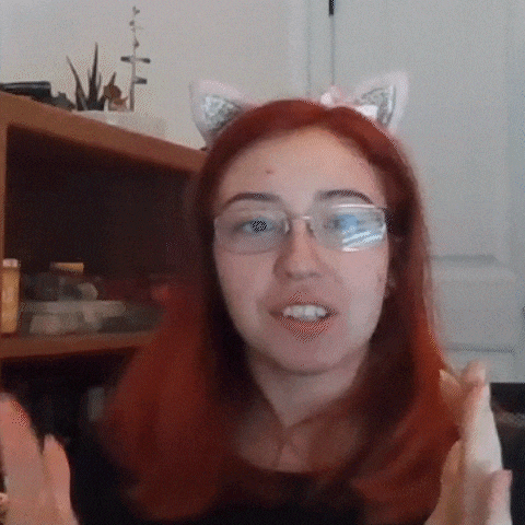 a woman with red hair and glasses is wearing cat ears and making a funny face .