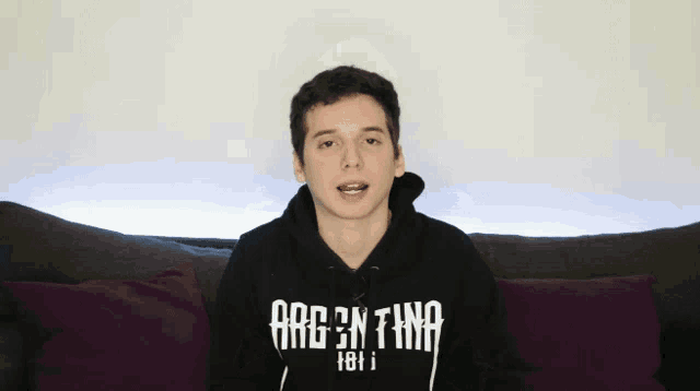 a man laying on a couch wearing a black hoodie that says brooklyn on it