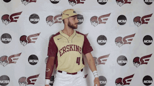 a baseball player for the ersking team stands in front of a ncaa banner