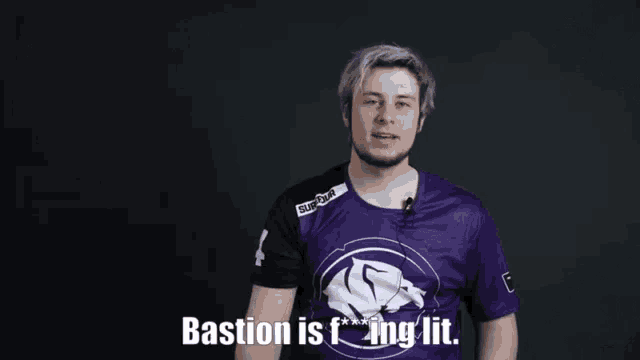 a man in a purple shirt is standing in front of a black background and says bastion is fucking lit .