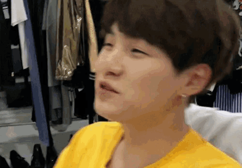 a woman in a yellow shirt is sitting in front of a closet full of clothes