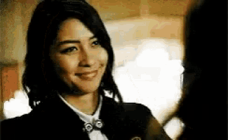 a woman is smiling and looking at the camera while wearing a suit and tie .