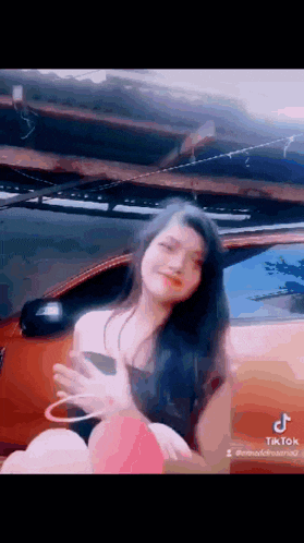 a woman is sitting in front of a car in a parking lot .