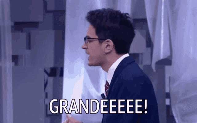 a man in a suit and tie is saying grandeeeee !