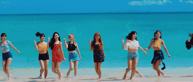 three women are dancing on the beach and one of them is wearing a red wig .