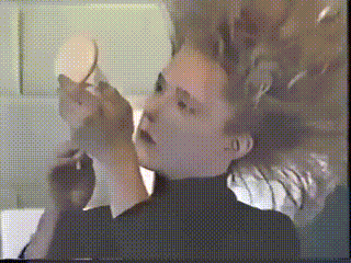 a woman looking at herself in a mirror with a blurred background