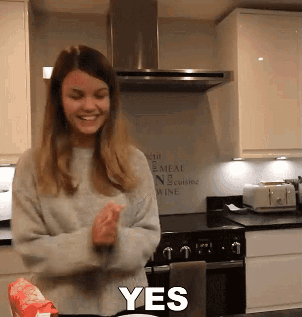 a woman standing in a kitchen with the word yes on the bottom