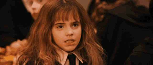 a young girl in a school uniform and tie is making a face .