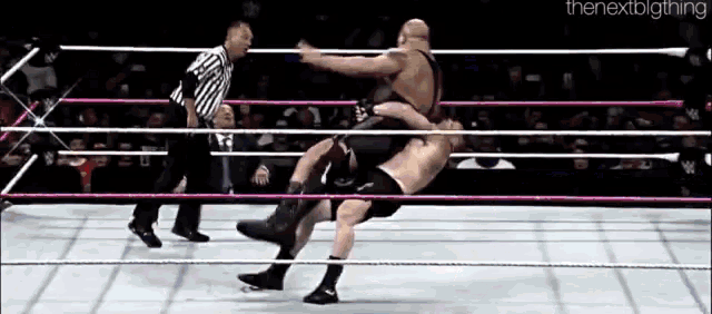 two men are wrestling in a wrestling ring with a referee watching