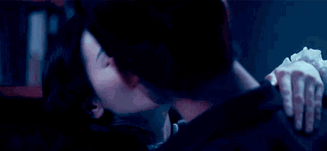a man and a woman are kissing in the dark .