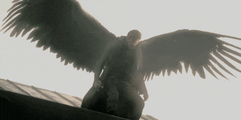 a man with wings is sitting on a roof
