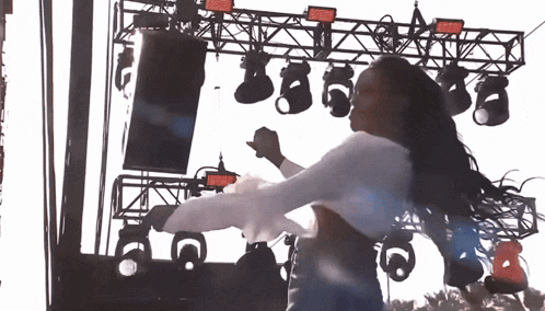 a woman in a white shirt is dancing on stage