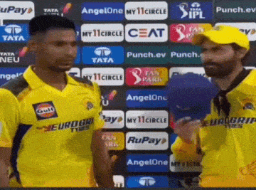 a group of cricket players are standing in front of a wall with advertisements for ceat and rupay .