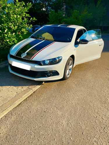 a white car with black and red stripes on the side is parked on gravel