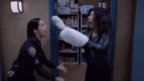 two police officers are fighting with a pillow and the nbc logo is in the background