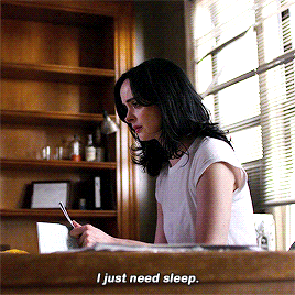 a woman is sitting at a desk with a book and says i just need sleep