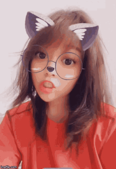 a girl wearing a red shirt and glasses with cat ears