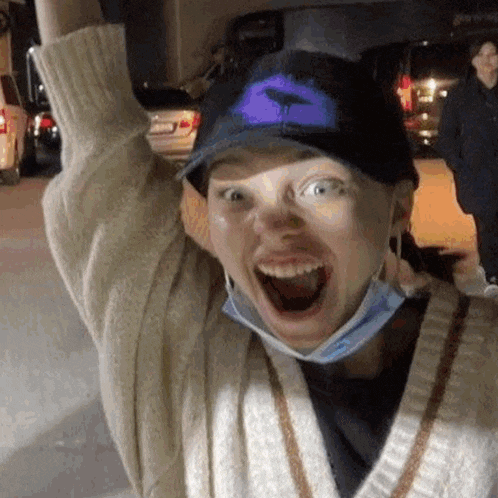 a woman wearing a hat and a mask is making a funny face with her mouth open .
