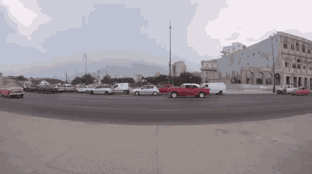 a red car is driving down a street next to a white van
