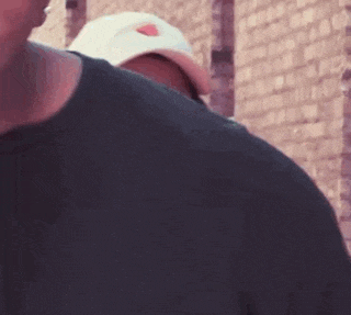 a man wearing a hat is standing next to another man .
