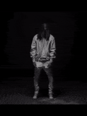 a black and white photo of a man with dreadlocks wearing a jacket .