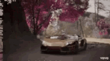 a car is driving down a road with pink trees in the background