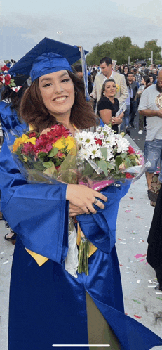 a woman in a graduation cap and gown is holding flowers