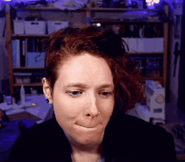 a woman with red hair and a nose ring is making a funny face