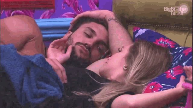 a man and a woman are laying on a bed and the woman is touching the man 's face